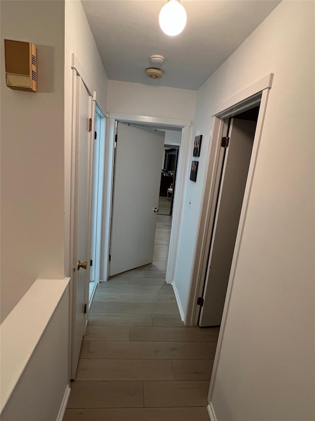 hallway featuring baseboards and wood finished floors