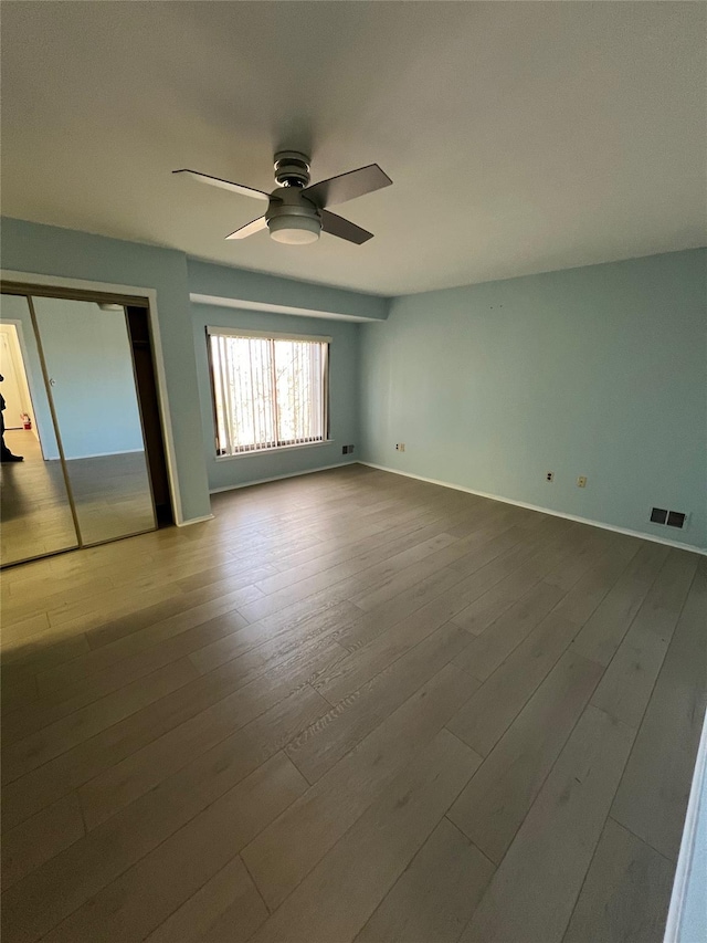 unfurnished bedroom featuring visible vents, baseboards, wood finished floors, and a ceiling fan