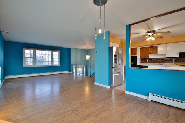 kitchen featuring decorative backsplash, open floor plan, stainless steel refrigerator with ice dispenser, and baseboard heating