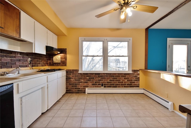 kitchen with baseboard heating, brick wall, black appliances, and a sink