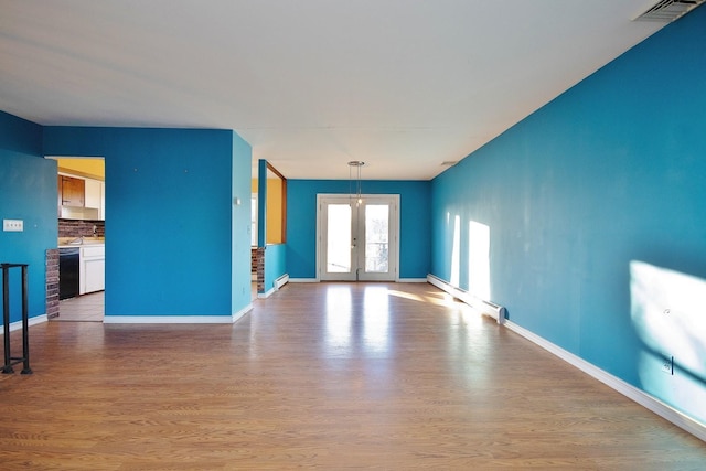 unfurnished living room featuring wood finished floors, french doors, visible vents, and a baseboard radiator