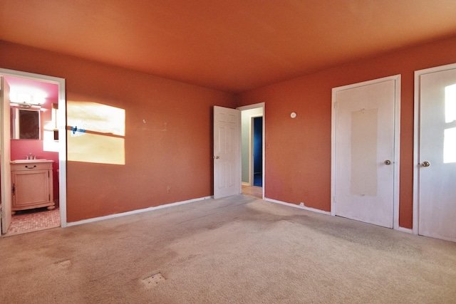 unfurnished bedroom featuring a sink, carpet, and ensuite bath