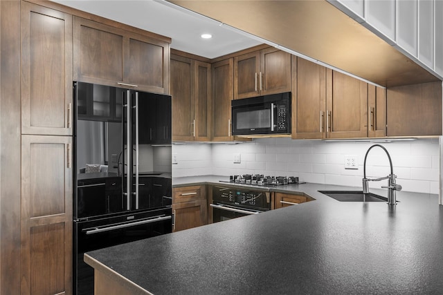 kitchen with decorative backsplash, dark countertops, black appliances, a sink, and recessed lighting