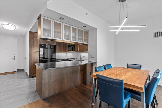 kitchen featuring tasteful backsplash, dark wood-type flooring, a peninsula, and black appliances