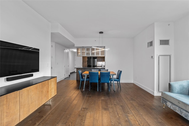 dining room with dark wood-style floors, visible vents, and baseboards