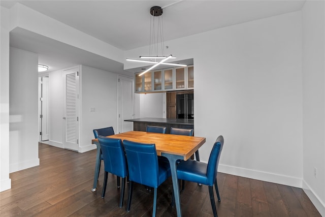 dining area with baseboards and dark wood finished floors