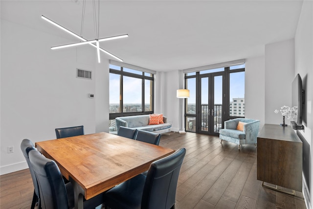 dining space featuring dark wood-type flooring, visible vents, baseboards, french doors, and a wall of windows