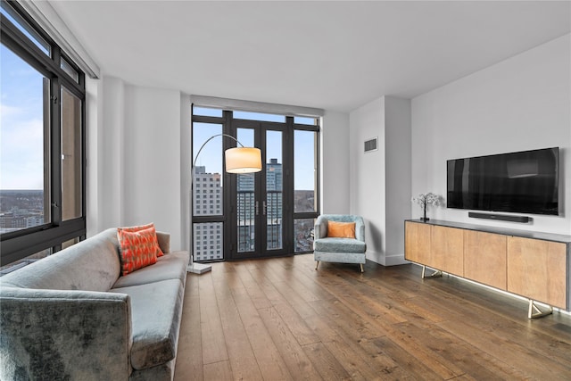 living room featuring french doors, wood-type flooring, visible vents, and floor to ceiling windows