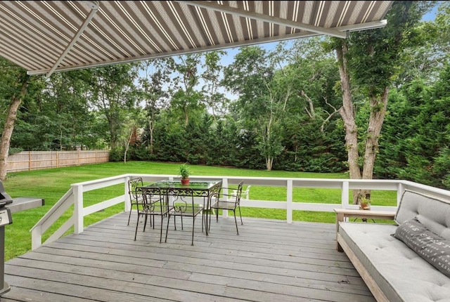 wooden deck featuring outdoor dining area, a lawn, and fence