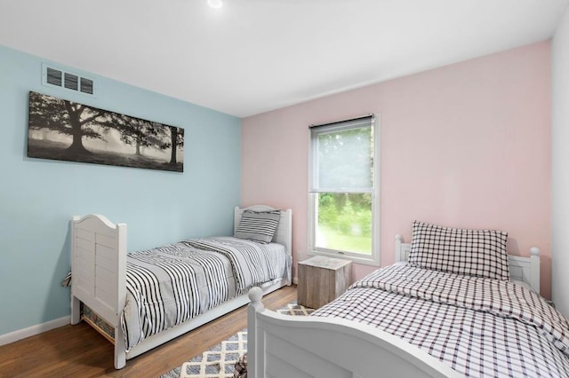 bedroom featuring wood finished floors, visible vents, and baseboards