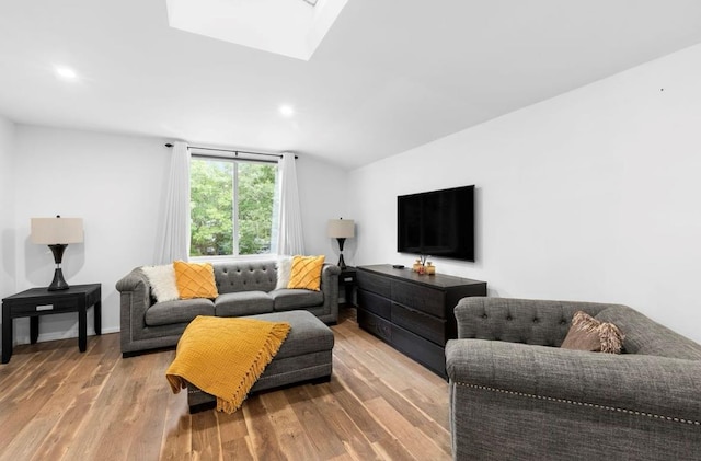 living area with baseboards, vaulted ceiling with skylight, wood finished floors, and recessed lighting