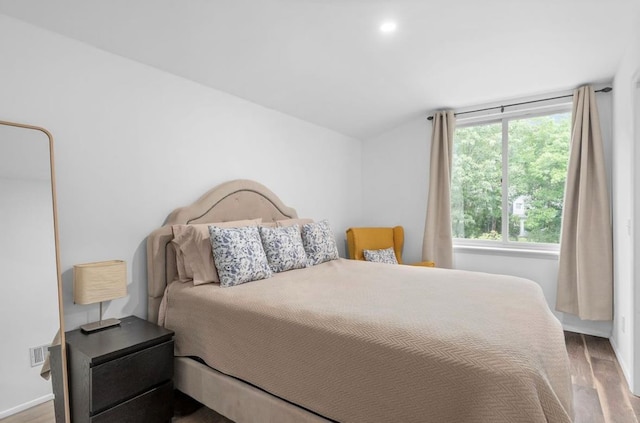 bedroom with visible vents, vaulted ceiling, and wood finished floors