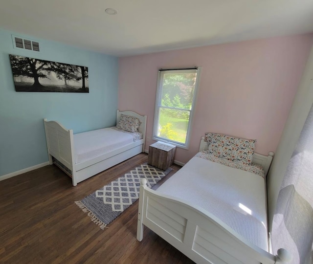 bedroom featuring visible vents, baseboards, and wood finished floors