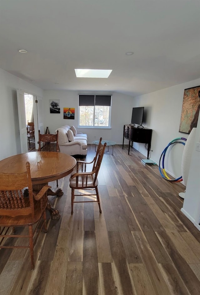 dining room featuring dark wood-style floors and a skylight