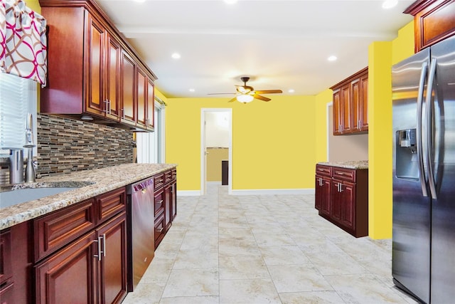 kitchen with reddish brown cabinets, light stone counters, backsplash, appliances with stainless steel finishes, and baseboards