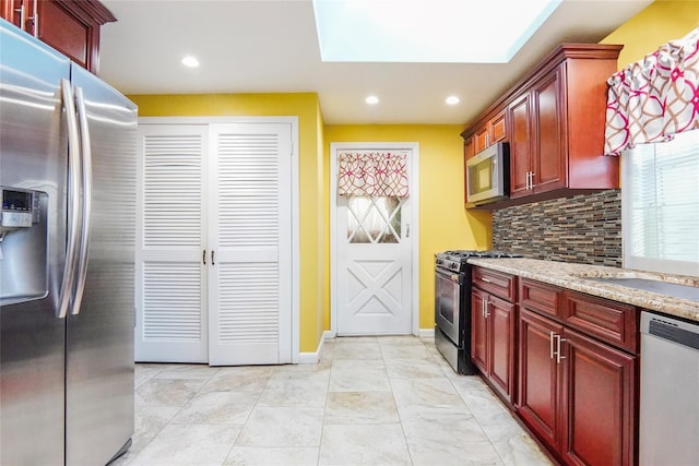 kitchen with reddish brown cabinets, light stone counters, recessed lighting, backsplash, and appliances with stainless steel finishes