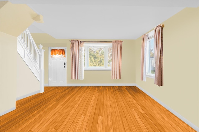 spare room featuring light wood-type flooring, stairway, and baseboards