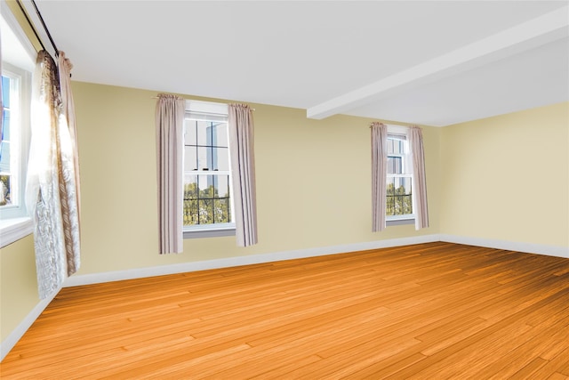 spare room with a healthy amount of sunlight, beamed ceiling, and wood finished floors