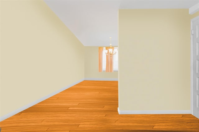 spare room with a chandelier, light wood-type flooring, and baseboards