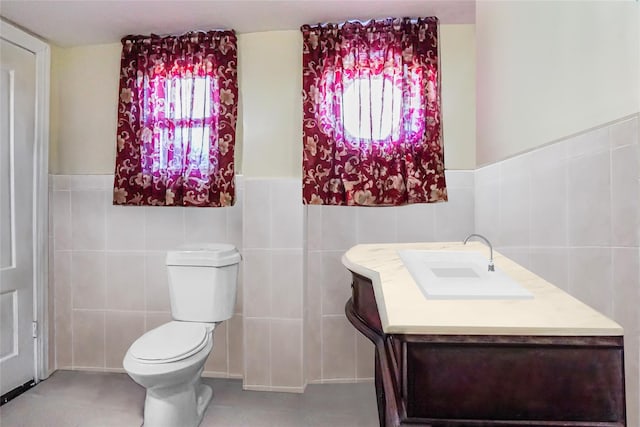 half bath with toilet, tile walls, and vanity