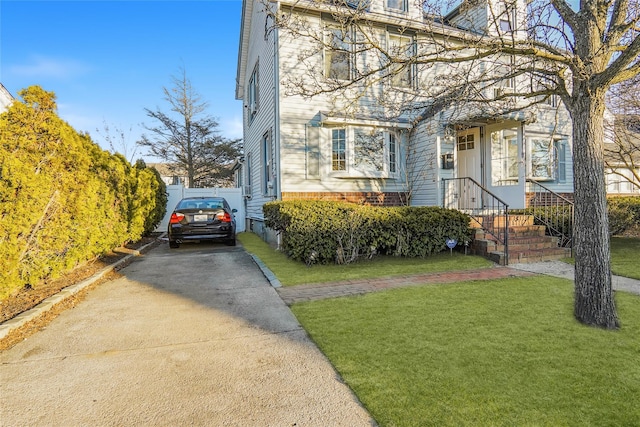 view of front of property with driveway, fence, and a front lawn