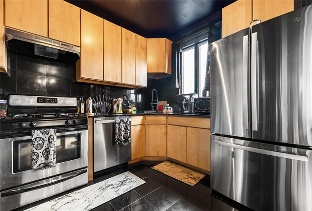 kitchen featuring dark tile patterned flooring, exhaust hood, appliances with stainless steel finishes, decorative backsplash, and dark countertops