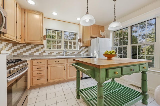 kitchen featuring light brown cabinets, a sink, decorative backsplash, pendant lighting, and stainless steel appliances