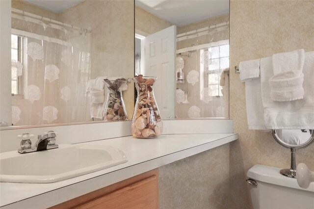 bathroom with curtained shower, toilet, and vanity