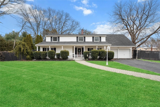 view of front facade featuring aphalt driveway, a porch, a chimney, and a front lawn