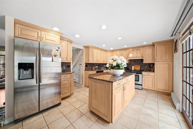 kitchen featuring tasteful backsplash, a kitchen island, premium range hood, dark stone countertops, and stainless steel appliances