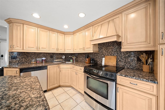 kitchen featuring backsplash, custom range hood, light tile patterned floors, appliances with stainless steel finishes, and a sink