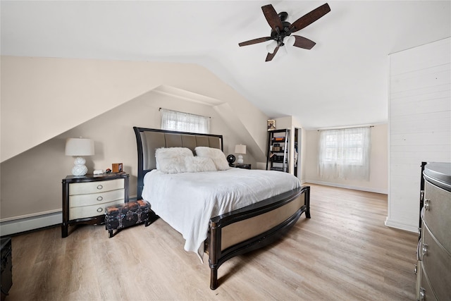 bedroom with a baseboard heating unit, vaulted ceiling, light wood-style floors, and a ceiling fan