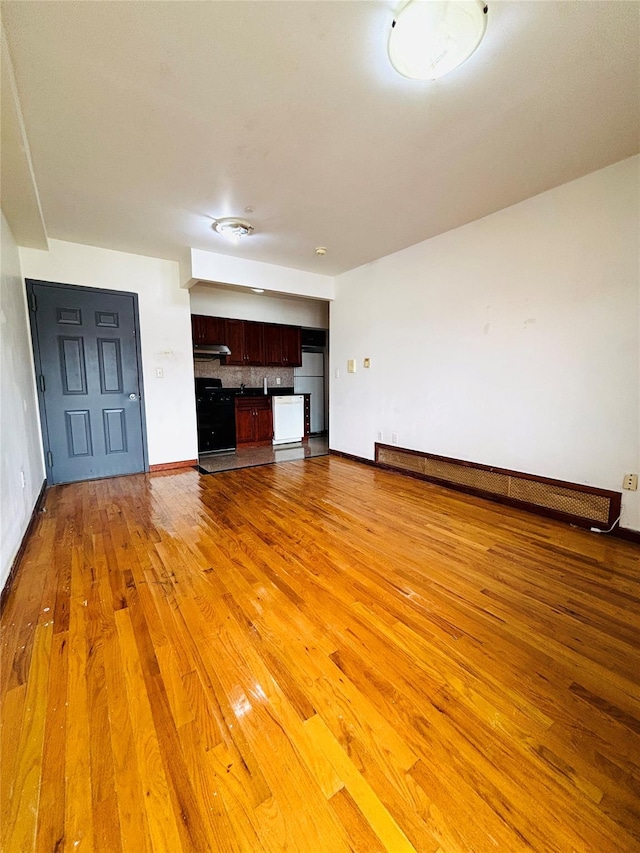 unfurnished living room with light wood-style flooring, baseboards, and baseboard heating