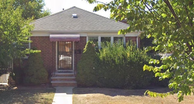 view of front of house with a shingled roof and brick siding