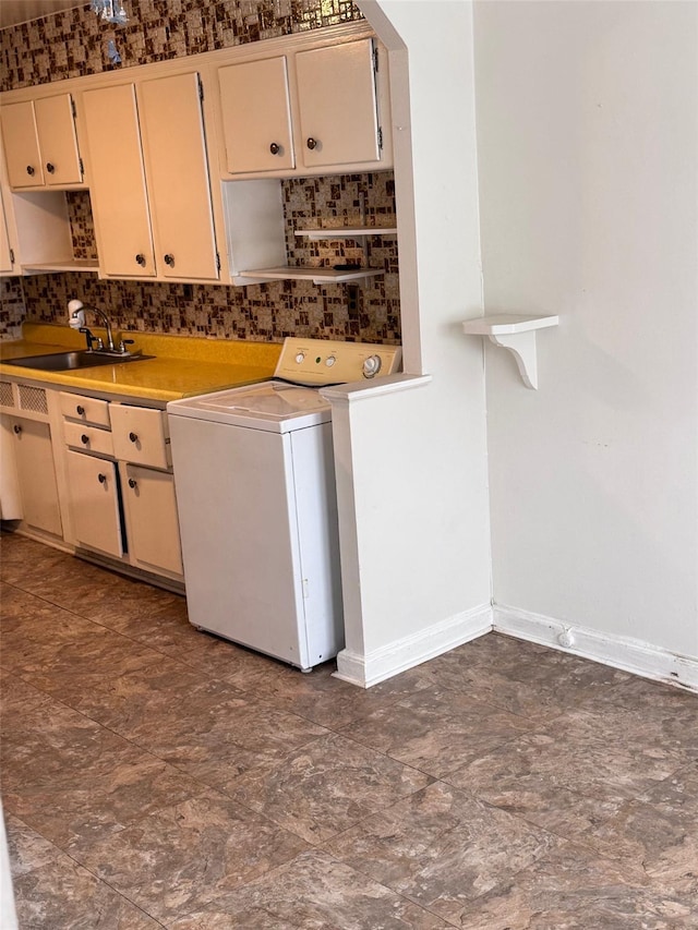 laundry area with laundry area, washer / clothes dryer, a sink, and baseboards