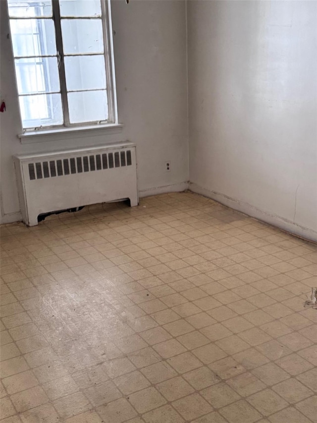 unfurnished room with light floors and radiator