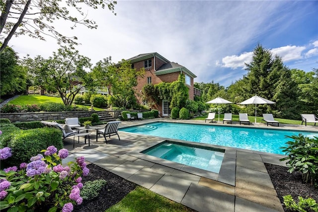 outdoor pool with a patio area and an in ground hot tub