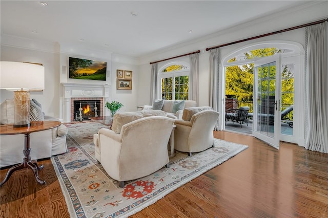 living room with ornamental molding, a brick fireplace, and wood finished floors