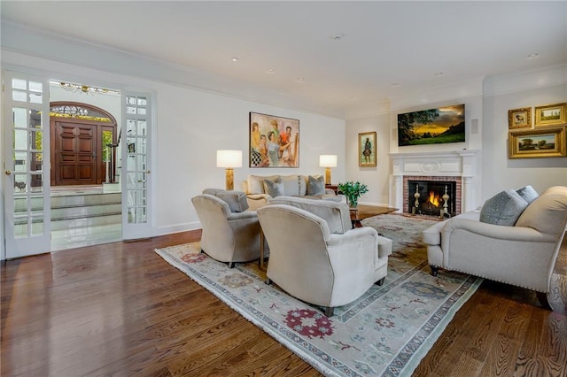 living area with baseboards, a fireplace, wood finished floors, and crown molding