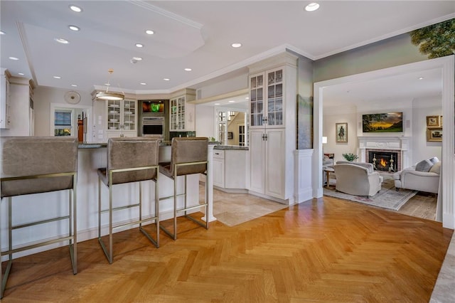 kitchen with glass insert cabinets, a breakfast bar, ornamental molding, a lit fireplace, and stainless steel oven