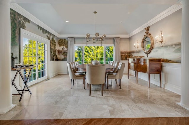 dining area featuring a wainscoted wall, ornamental molding, a notable chandelier, and ornate columns