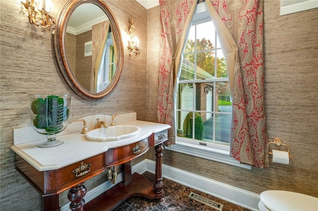 bathroom featuring visible vents, toilet, vanity, baseboards, and wallpapered walls