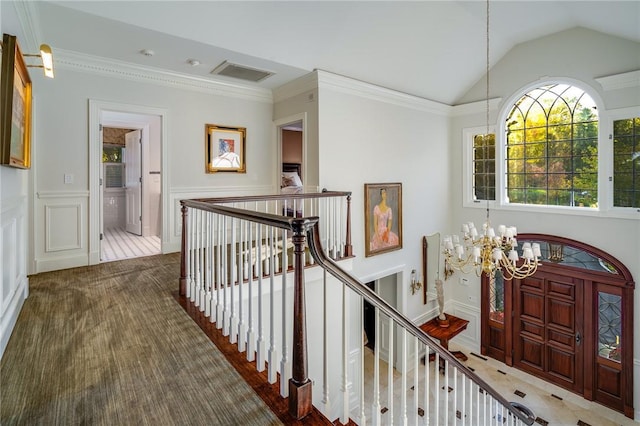 entrance foyer featuring vaulted ceiling, ornamental molding, visible vents, and a notable chandelier