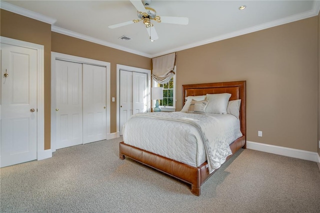 bedroom featuring baseboards, two closets, visible vents, and crown molding