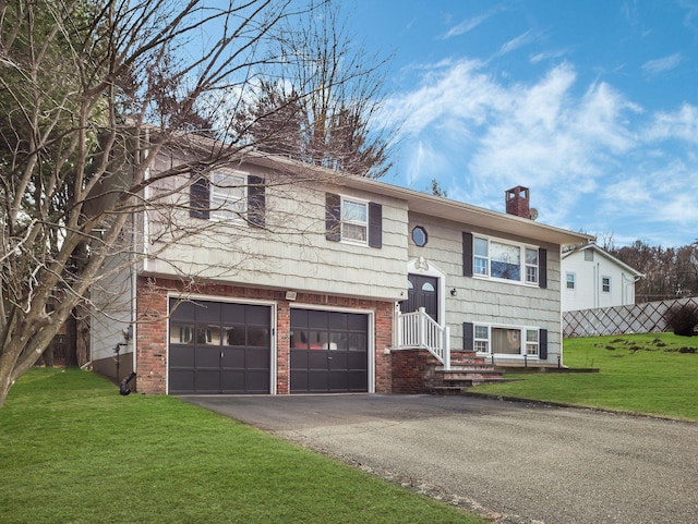 raised ranch with driveway, a front yard, a garage, brick siding, and a chimney