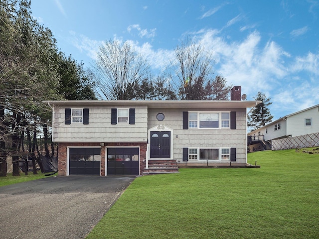 split foyer home featuring an attached garage, a chimney, a front lawn, aphalt driveway, and brick siding