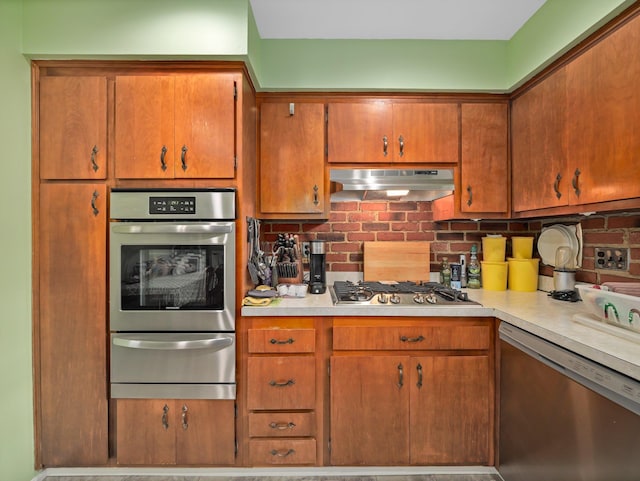 kitchen with under cabinet range hood, appliances with stainless steel finishes, light countertops, and a warming drawer