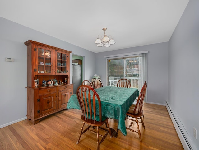 dining space with a baseboard heating unit, an inviting chandelier, light wood-style flooring, and baseboards