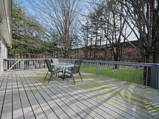 deck featuring outdoor dining space and a lawn