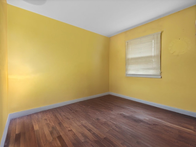 empty room featuring baseboards and dark wood finished floors